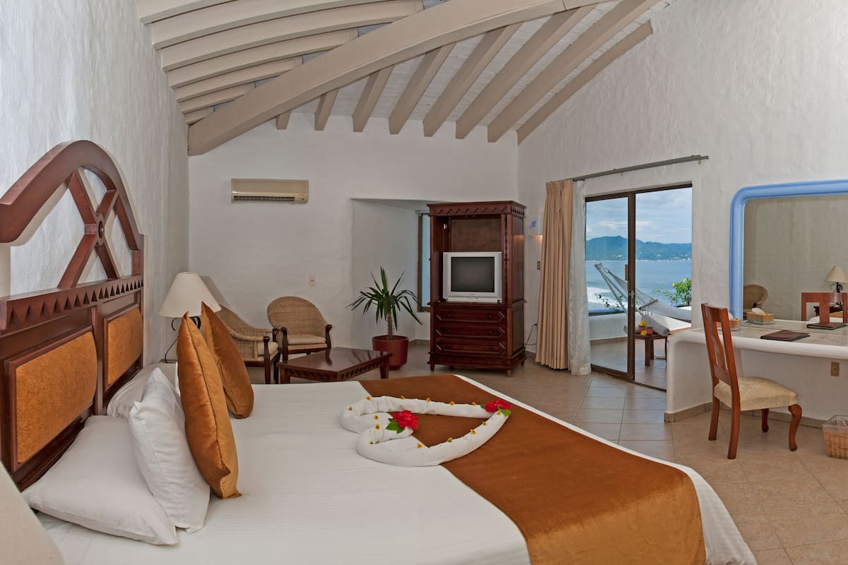 Ein Hotelzimmer mit Bett, Schreibtisch, Sessel, Fernseher und Meerblick.