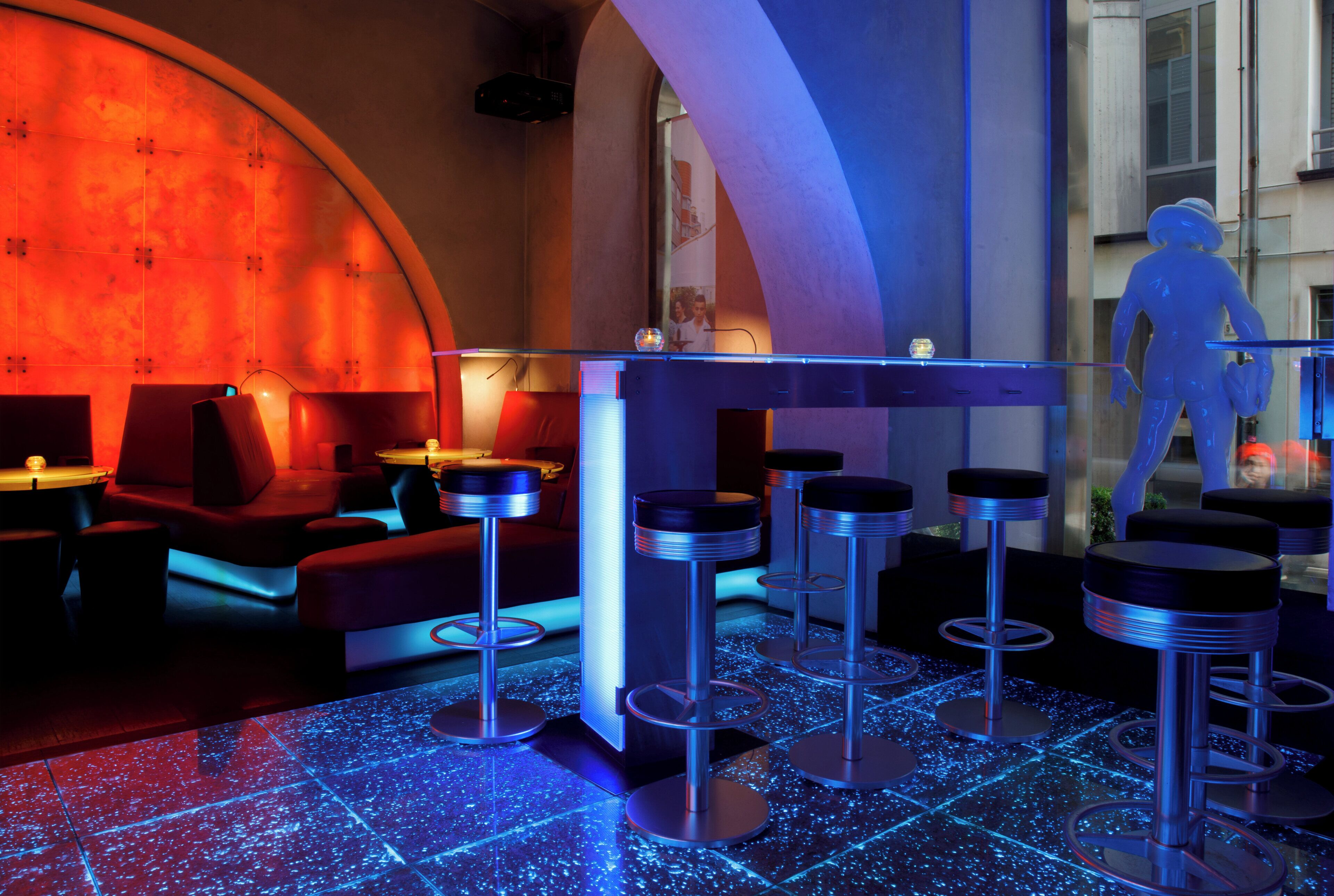 Un área de bar con taburetes y un suelo iluminado con neón.