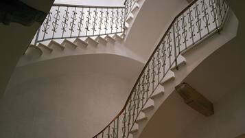 Eine Wendeltreppe mit aufwendiger Metallreling und weißen Wänden.