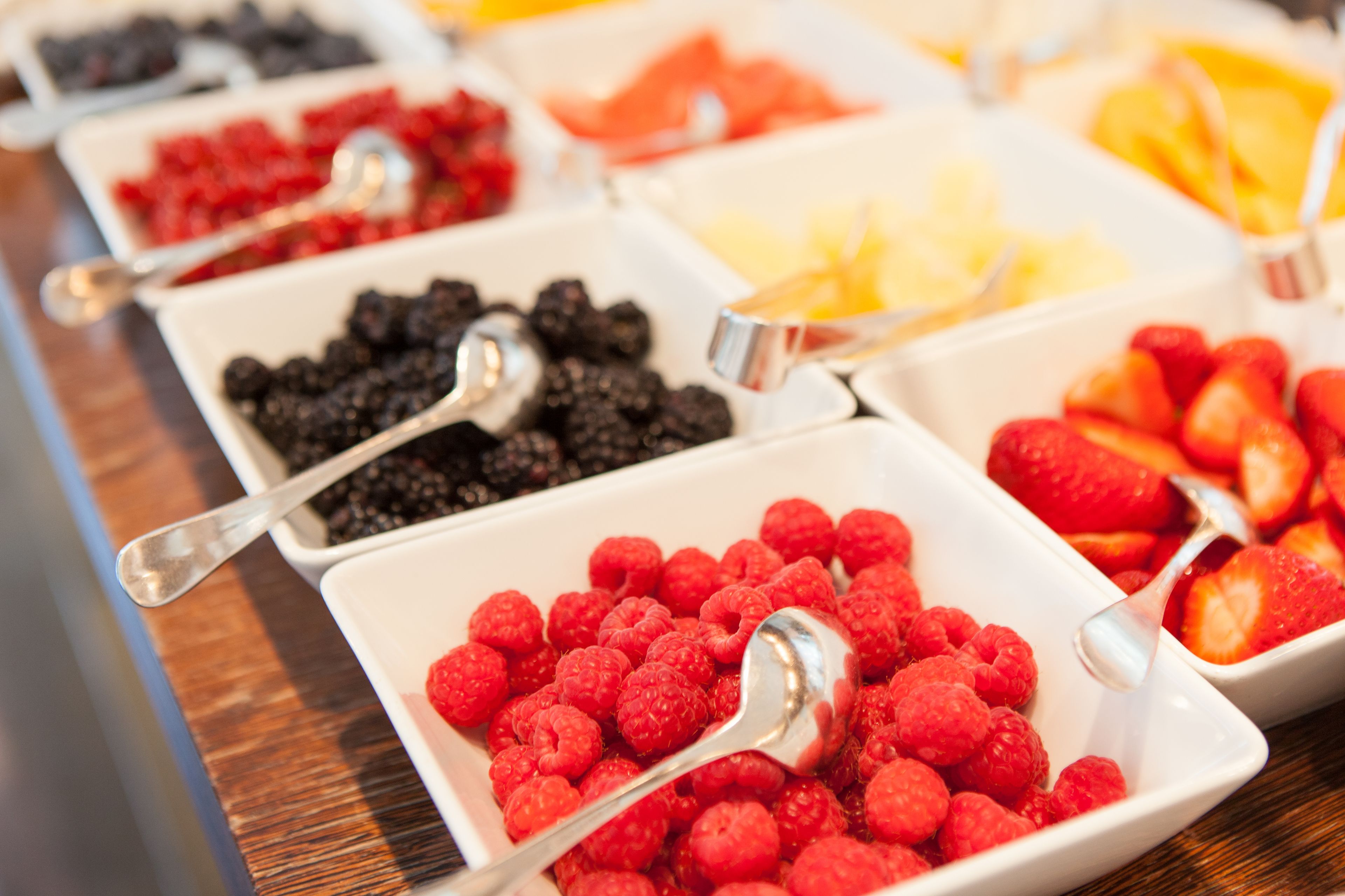 Ein Buffet mit verschiedenen Früchten und Beeren, darunter Himbeeren, Brombeeren und Obstspalten.