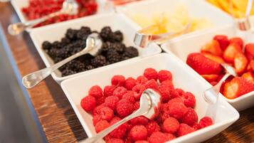 Ein Buffet mit verschiedenen Früchten und Beeren, darunter Himbeeren, Brombeeren und Obstspalten.