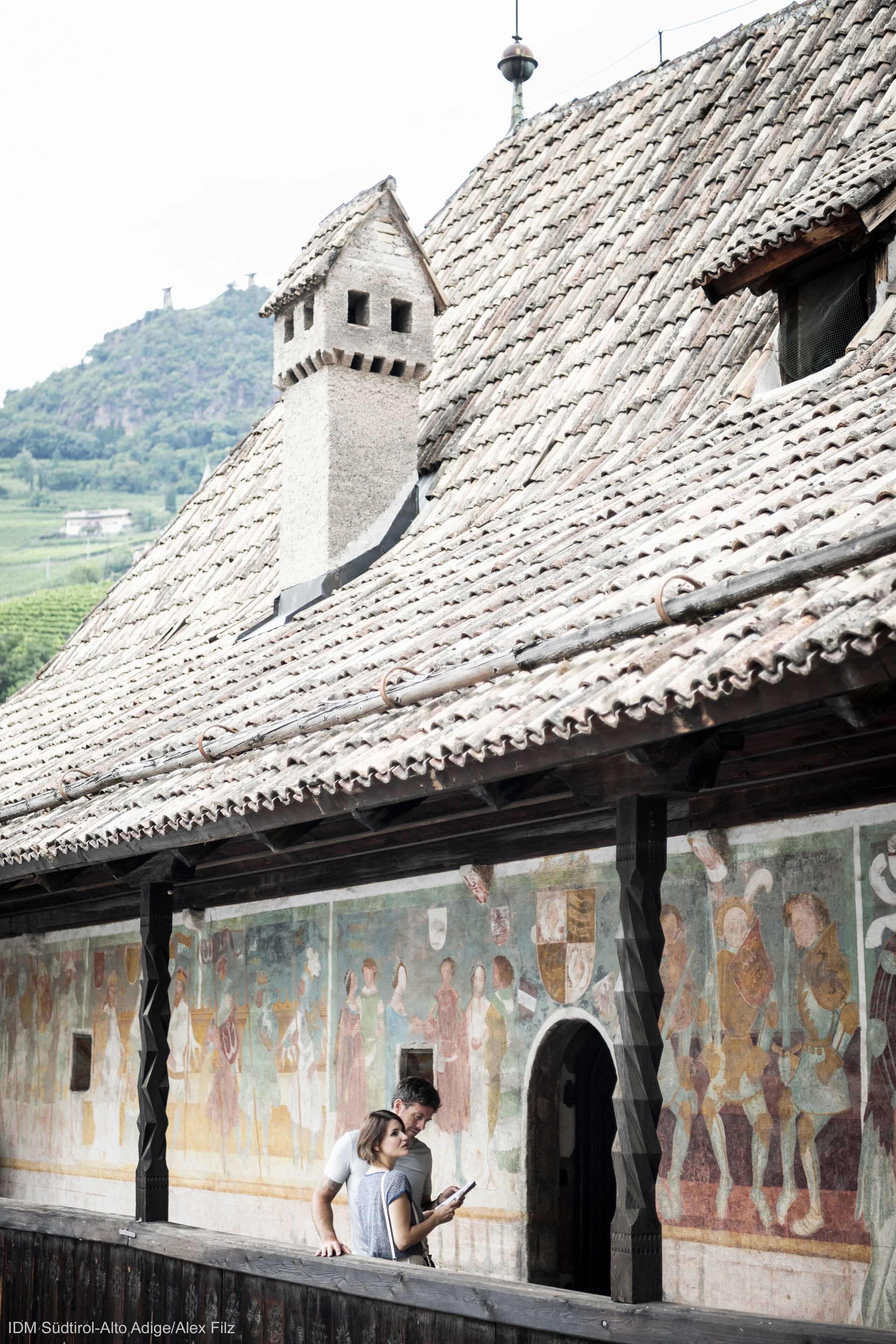Un edificio storico con tetto in tegole e un murale raffigurante figure.