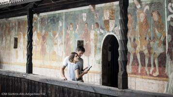 Un edificio storico con tetto in tegole e un murale raffigurante figure.