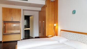 A hotel room with a bed, wooden wardrobe, and a nightstand with a lamp.
