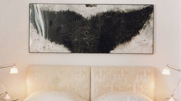 Una cama doble con un cabecero estampado, dos lámparas de noche y una obra de arte abstracta de gran tamaño en la pared.