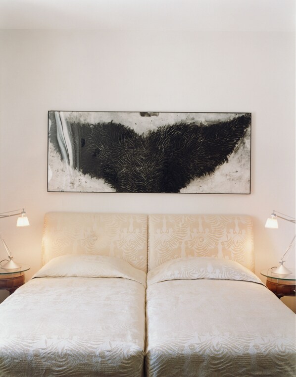 A double bed with a patterned headboard, two bedside lamps, and a large abstract artwork on the wall. - Hotel Greif, a Member of Design Hotels (Bolzano)
