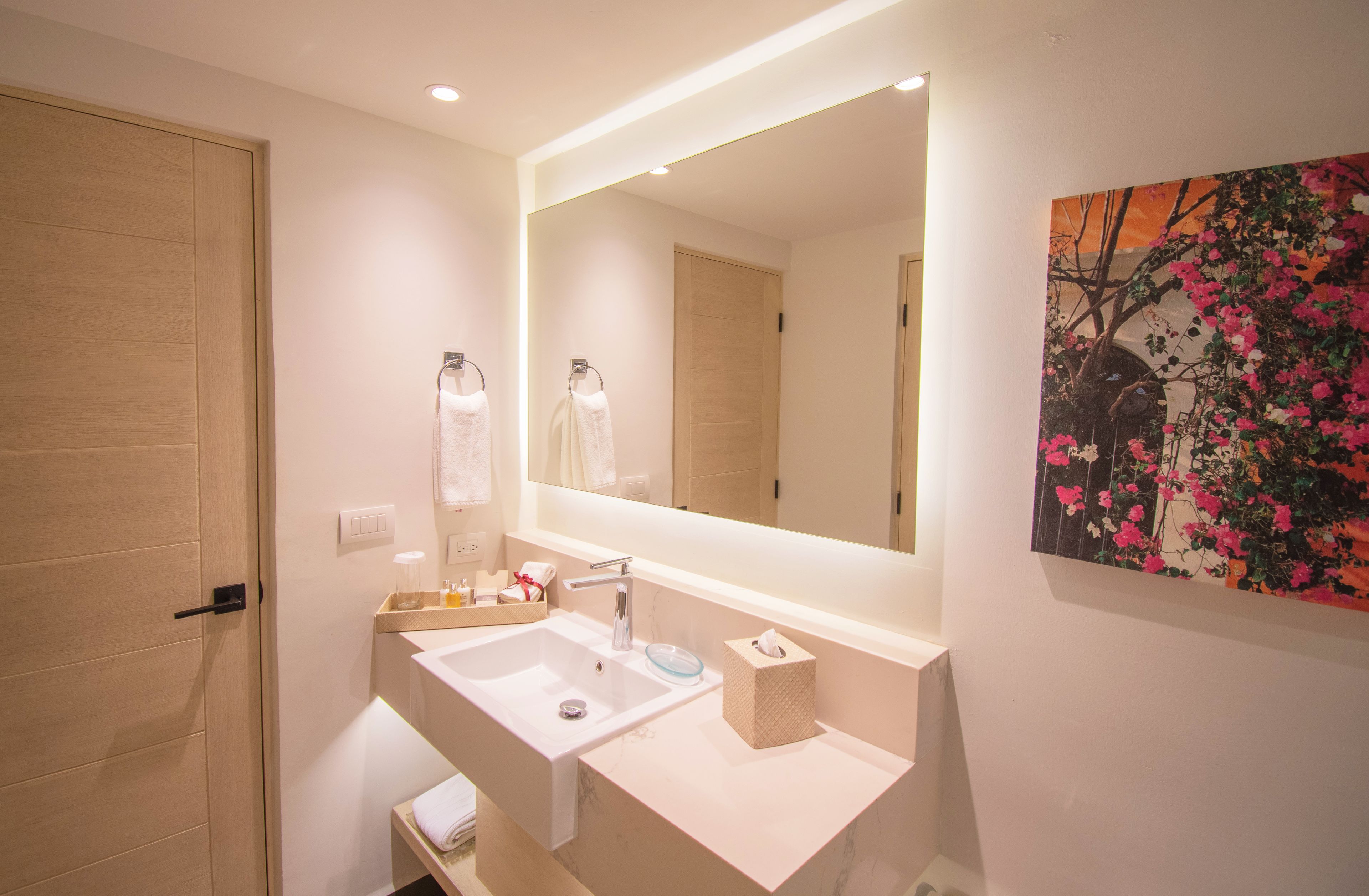 A modern bathroom with a large mirror, a sink, and a towel rack.