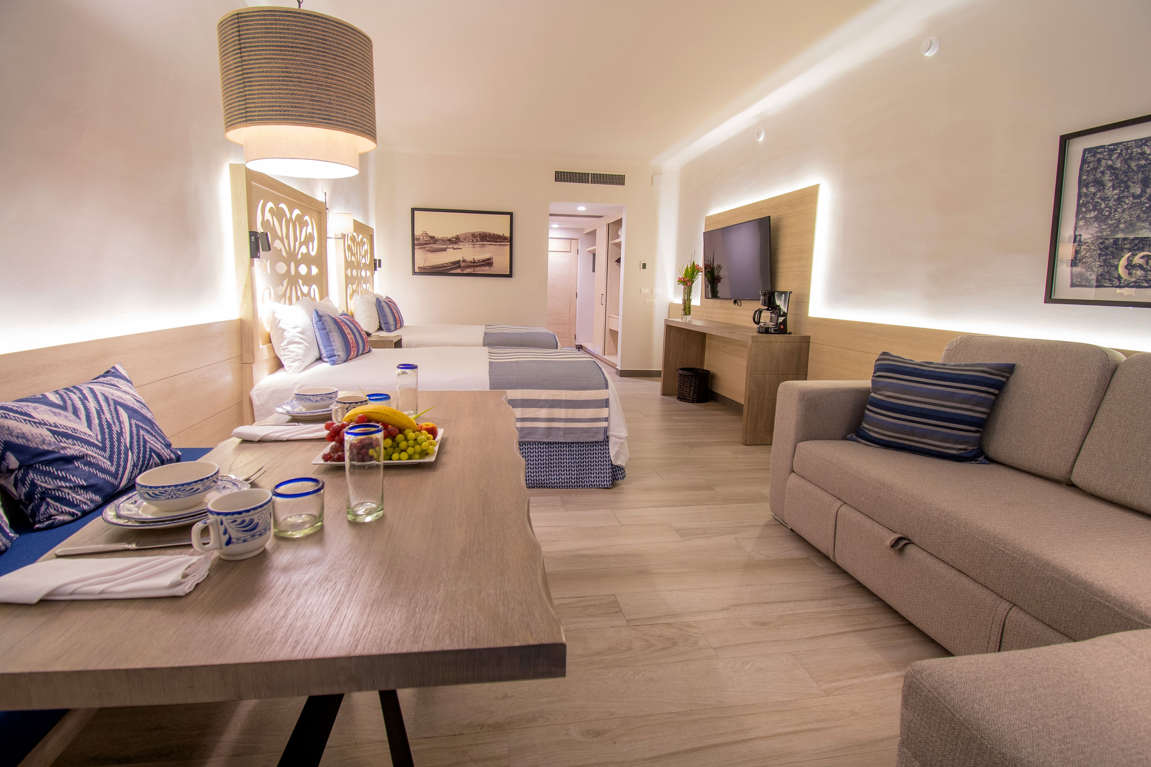 Una habitación de hotel moderna con comedor, sofá, televisión y cama con vista.