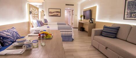 Una habitación de hotel moderna con comedor, sofá, televisión y cama con vista.