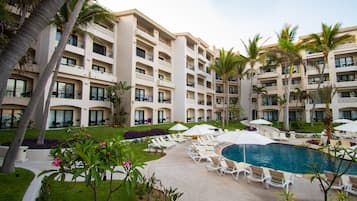 Un hotel con varios balcones, piscina y sillones de descanso.