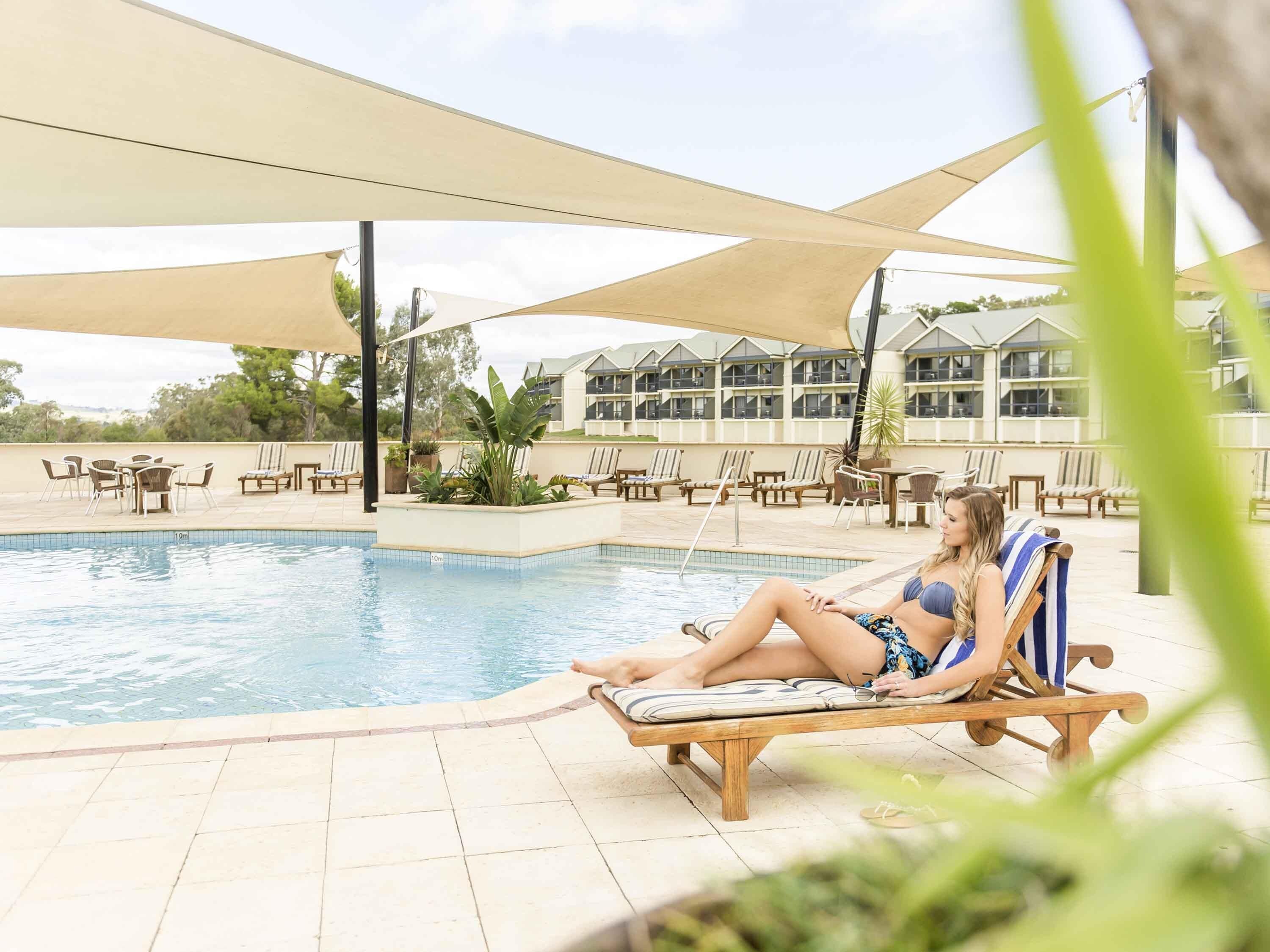 Un área junto a la piscina con sillones de descanso y una piscina.