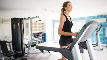 Een fitnessruimte met trainingsapparatuur, een loopband en gewichten.