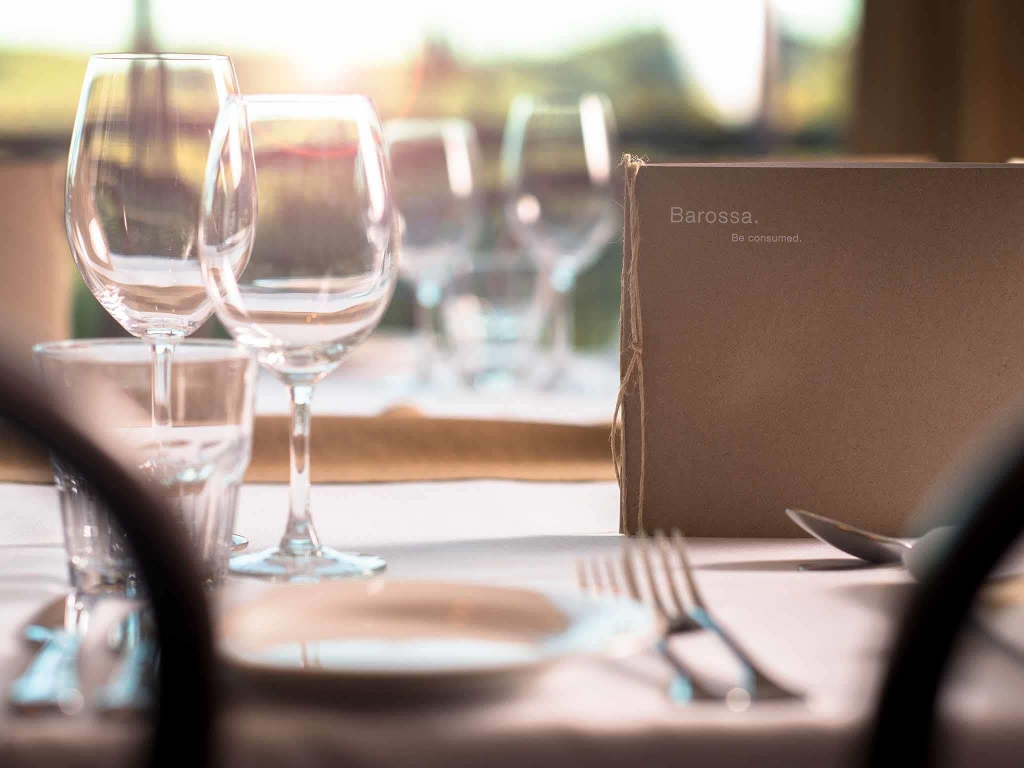 A table set with wine glasses, a menu, and cutlery, suggesting a dining setting.