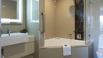 A modern bathroom with a glass-enclosed shower, a white bathtub, and a sink with a mirror above it.