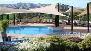 Zona de piscina con sillas de descanso y vistas a colinas.
