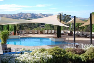 Área de piscina com cadeiras de descanso e vista para colinas.
