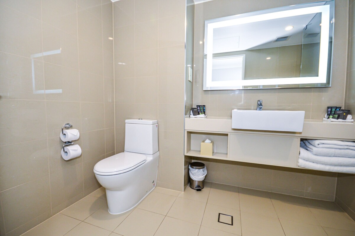 Un baño moderno con inodoro, lavamanos y espejo.