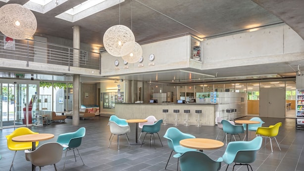A spacious indoor area with multiple seating arrangements, a kitchen area, and a mezzanine level.