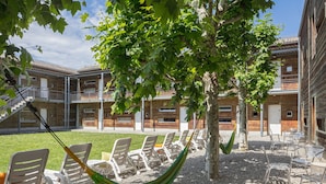 A courtyard with outdoor seating, a hammock, and a building with multiple balconies.
