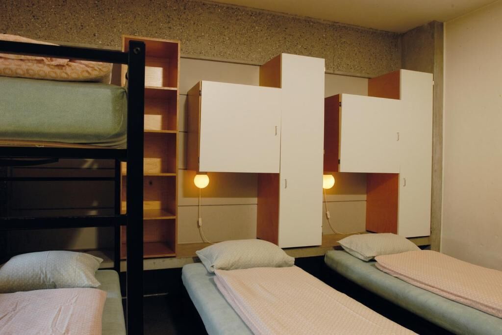 A dormitory room with bunk beds, a desk, and built-in wardrobes.