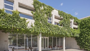 A building with a modern design, featuring a covered outdoor seating area with benches and planters.
