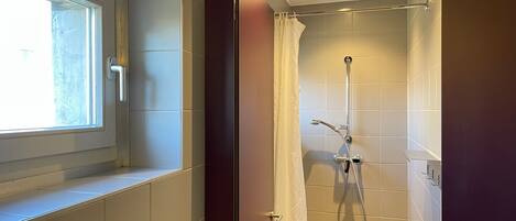 A bathroom with a shower, a window, and a door.