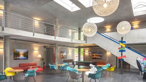 A spacious indoor area with a pool table, multiple seating arrangements, and a staircase leading to an upper level.