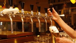 A bar with multiple taps and a hand holding a bottle. - Hotel Kaiserhof (Wesel)