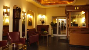 A hotel lobby with leather chairs, a fireplace, and a reception desk. - Hotel Kaiserhof (Wesel)