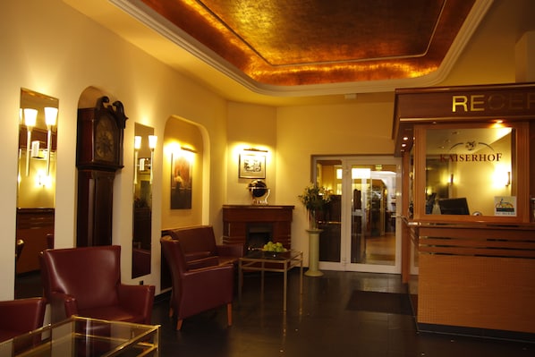 A hotel lobby with leather chairs, a fireplace, and a reception desk.