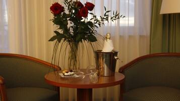 A table with a vase of red roses, a champagne bottle, and a glass of champagne.