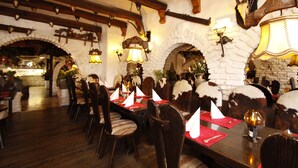 A restaurant with wooden tables and chairs, red placemats, and decorative wall sconces. - Hotel Kaiserhof (Wesel)