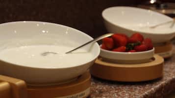 Tazones de yogur con una cuchara y fresas sobre una encimera.