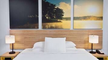 A hotel room with a bed, two bedside tables with lamps, and three framed pictures on the wall.