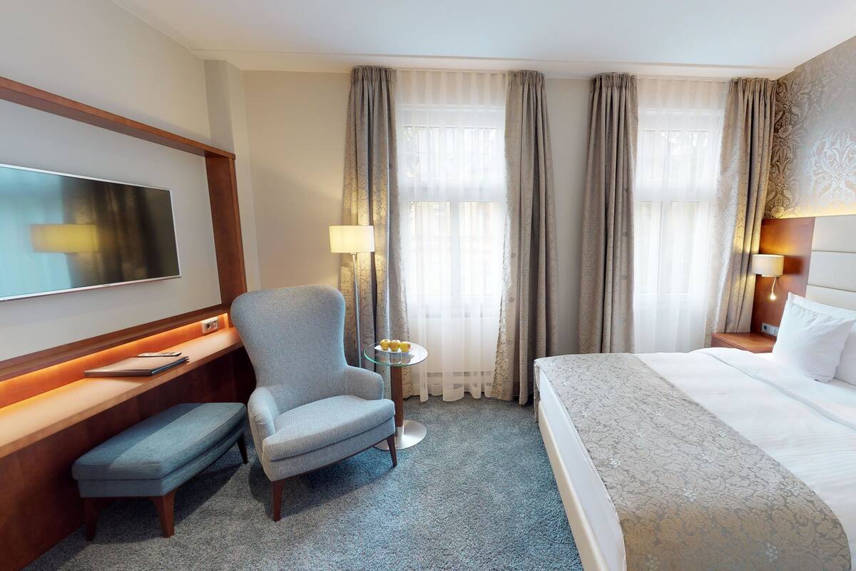 Une chambre d’hôtel comprenant un lit, un bureau avec une chaise, une télévision et une lampe.