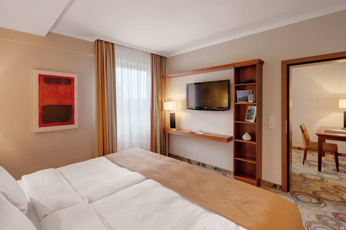 Une chambre d’hôtel comprenant un lit, une télévision, un bureau avec une chaise et une bibliothèque.