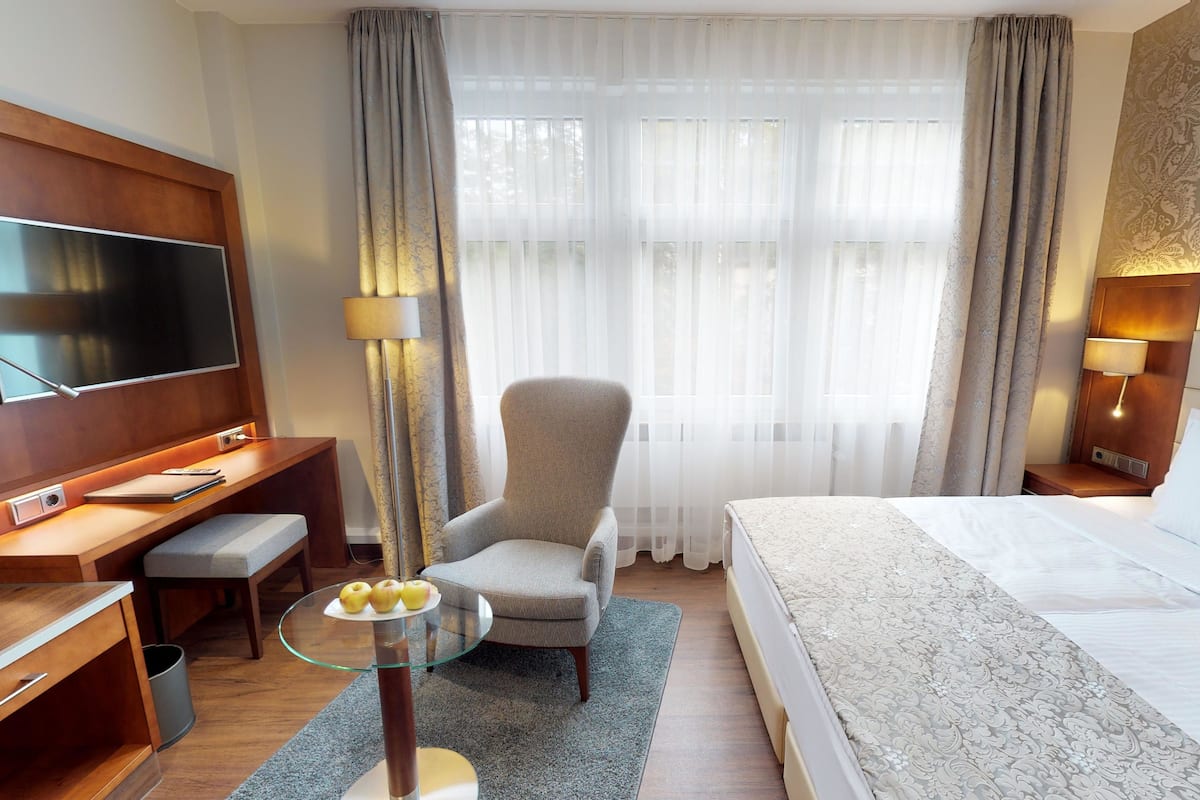 Une chambre d’hôtel avec un lit, un bureau et une chaise, une télévision et une lampe.
