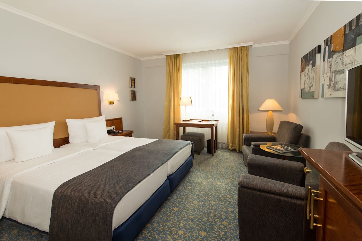 Une chambre d’hôtel avec un grand lit, un bureau, une chaise, une télévision et une petite table.