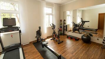 Un gimnasio en casa con cinta de correr, bicicletas estáticas y pelotas de ejercicios.