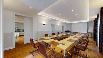 Een vergaderzaal met een lange tafel, stoelen en een projectiescherm.
