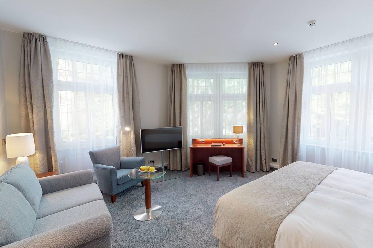 Une chambre d’hôtel avec un lit, un bureau avec une télévision, une chaise et une lampe.