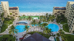 Un resort con dos piscinas grandes, una playa y vista al océano.