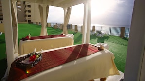 Una habitación con dos camas, césped artificial verde y vista al mar.