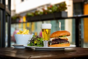 A meal consisting of a burger, fries, a salad, and a beer on a wooden table. - Kilkenny Ormonde Hotel (Kilkenny)