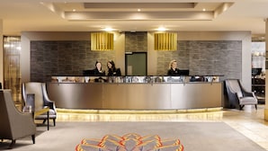 Un espace d’accueil au design moderne, comprenant un comptoir de réception, deux réceptionnistes et un tapis à motifs.