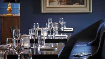 A dining area with tables set for a meal, featuring clear glassware and a framed picture on the wall.