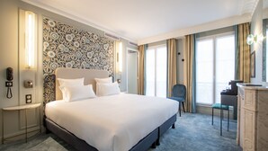 Habitación de hotel con una cama grande, un escritorio, una silla y un adorno en la pared.