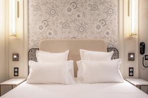 A hotel room with a bed, two bedside tables, a telephone, and wall-mounted light fixtures.