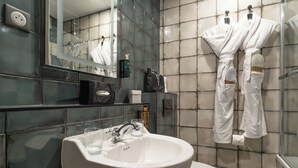 Un baño moderno con un lavamanos blanco, un espejo y un box de ducha de cristal.