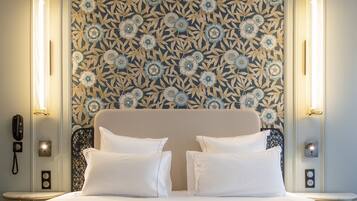 A hotel room with a large bed, two bedside tables, a telephone, and a decorative wall with a floral pattern.